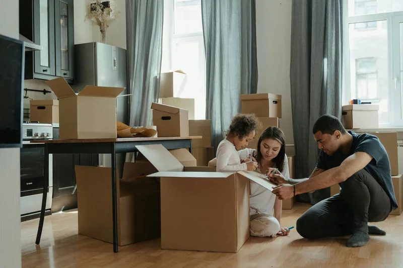 Adults and a child unpacking boxes in a home.
