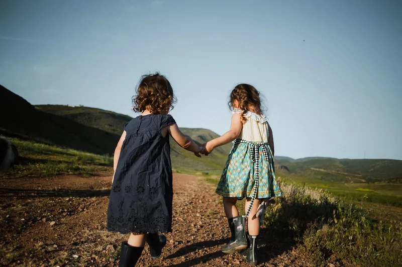 Dos niñas tomadas de la mano en un sendero de una colina