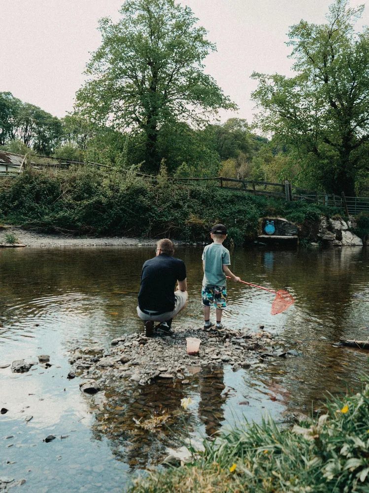 An adult and a child standing in shallow water.