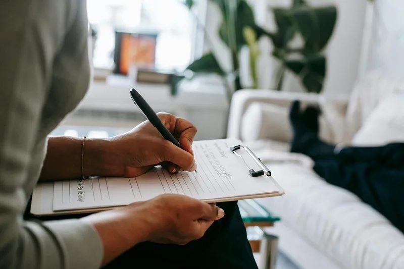 Person writing notes on a clipboard.