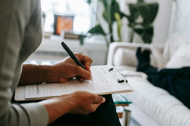 Persona escribiendo notas en un portapapeles.