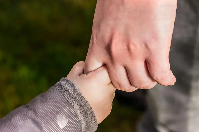 A child holding an adult’s hand.