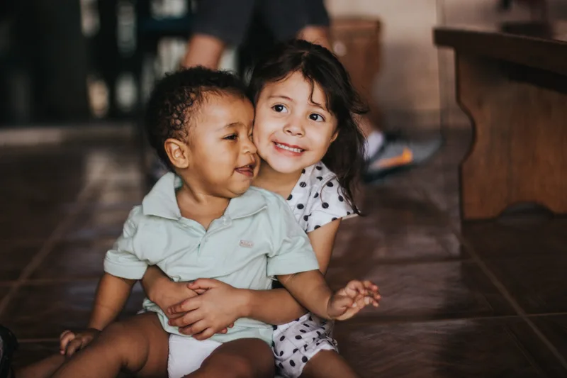child and baby smiling sitting on floor