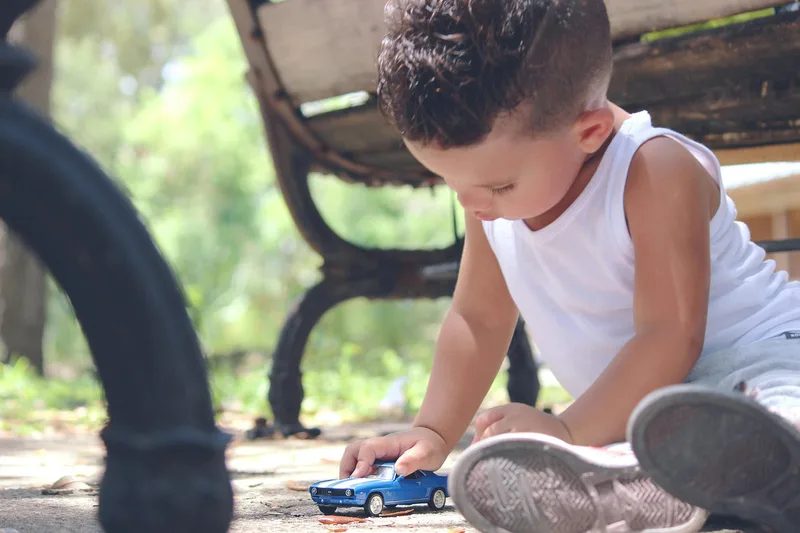 Young boy playing with a toy car on the ground