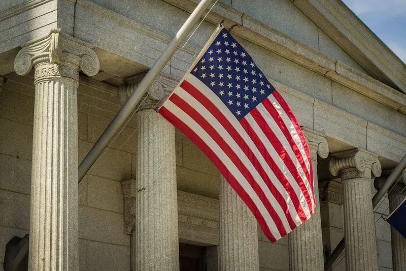 American flag outside a building with stone columns.