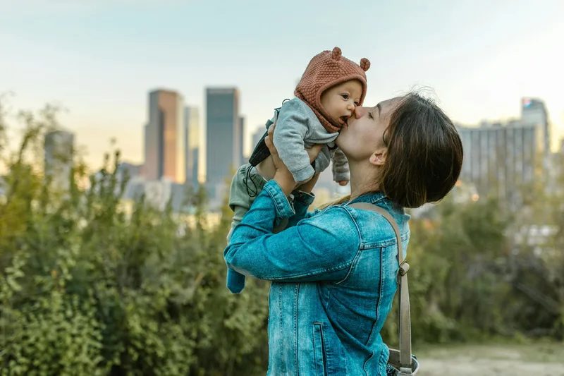 Adult kissing a child in a park.