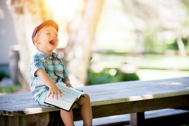 A young child sitting on a wooden bench.