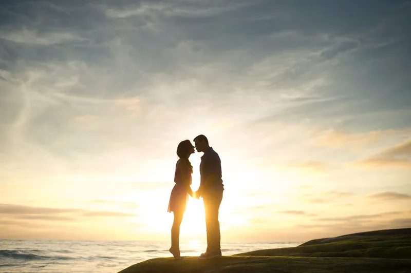 silhouette of couple kissing on beach