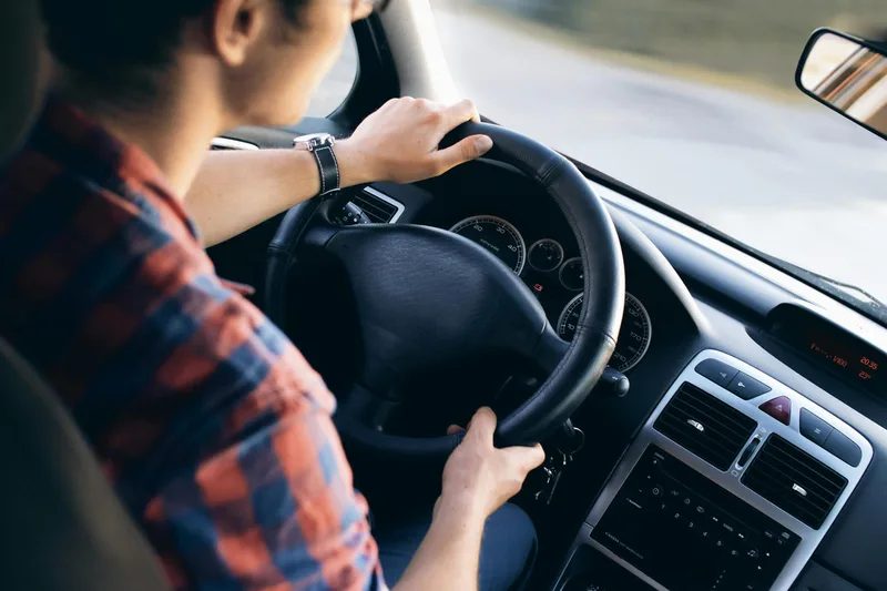 A driver’s hands on a steering wheel.
