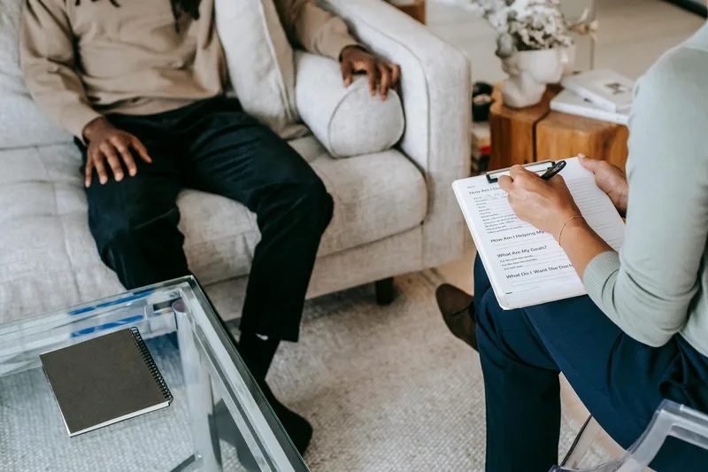 A person taking notes during a seated conversation.