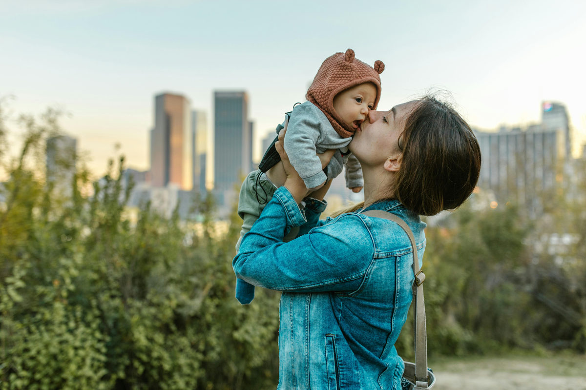 Adult kissing a child in a park.