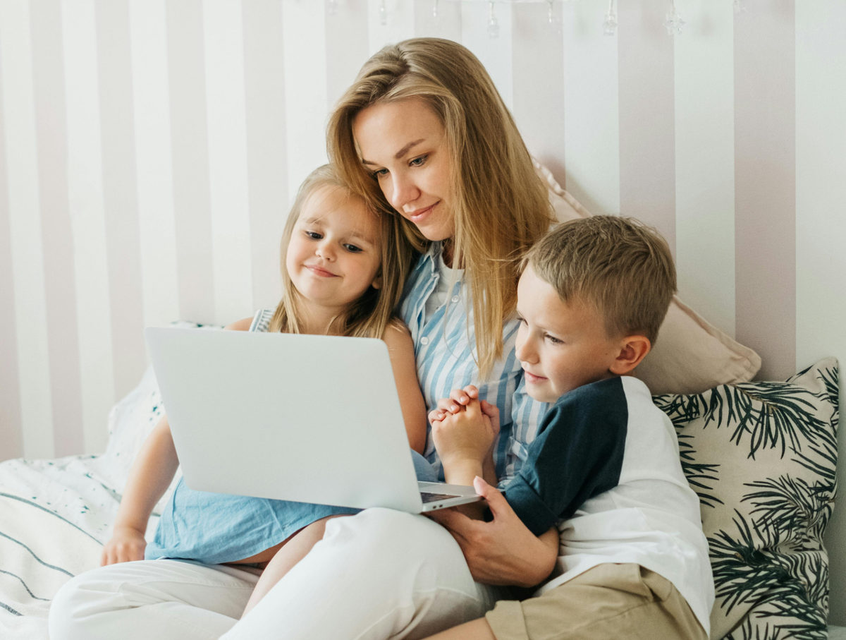 Adult and two children looking at a laptop