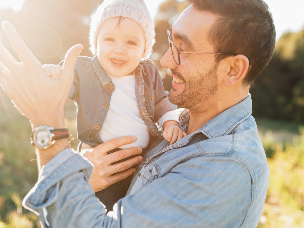 Adult holding a smiling child outdoors