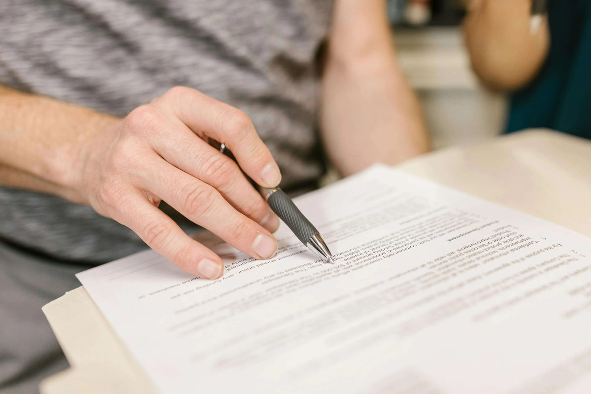 Hand holding a pen over a printed document.
