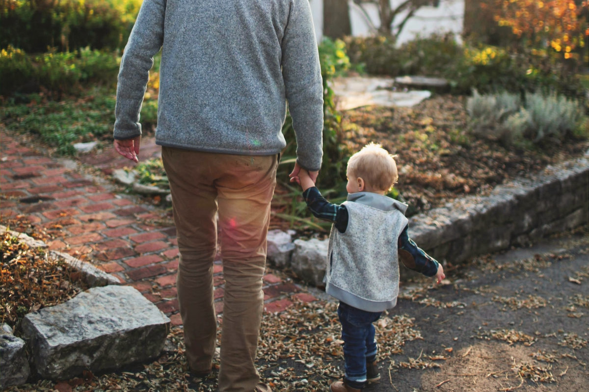 Un adulto y un niño caminando por una zona boscosa.