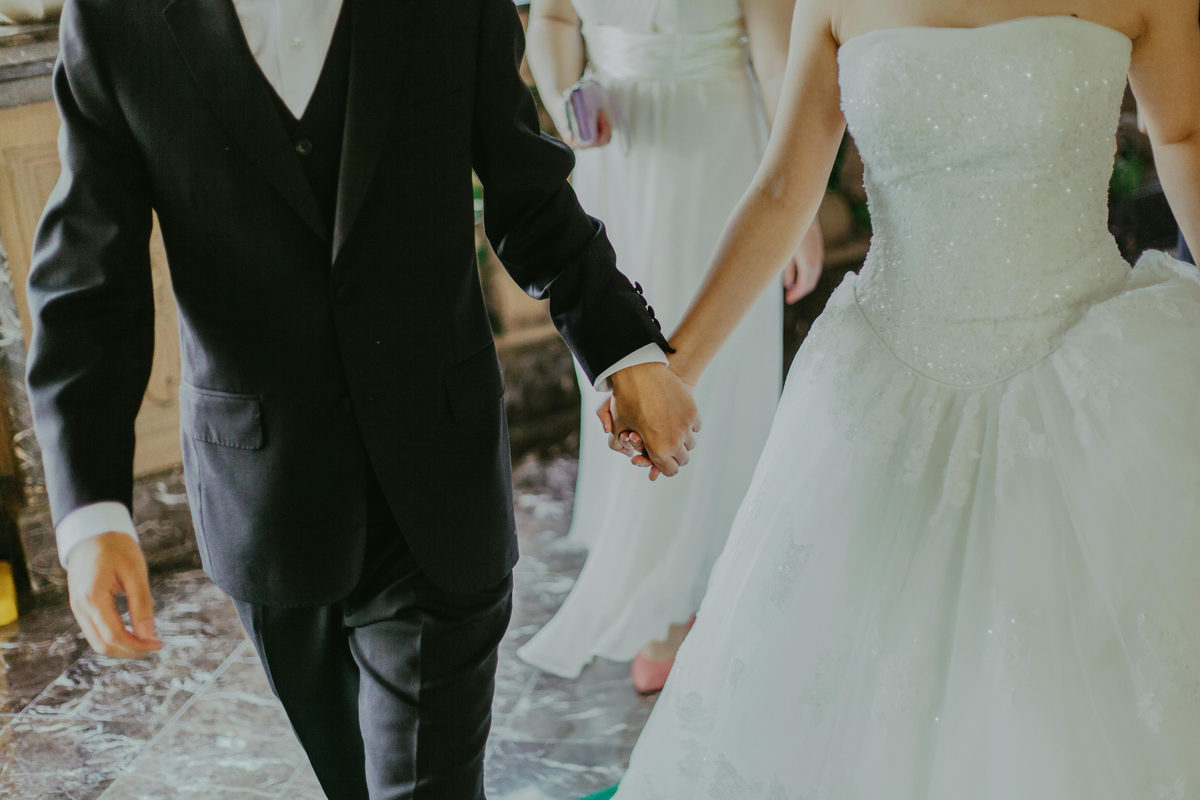 Dos personas vestidas de boda tomadas de la mano.