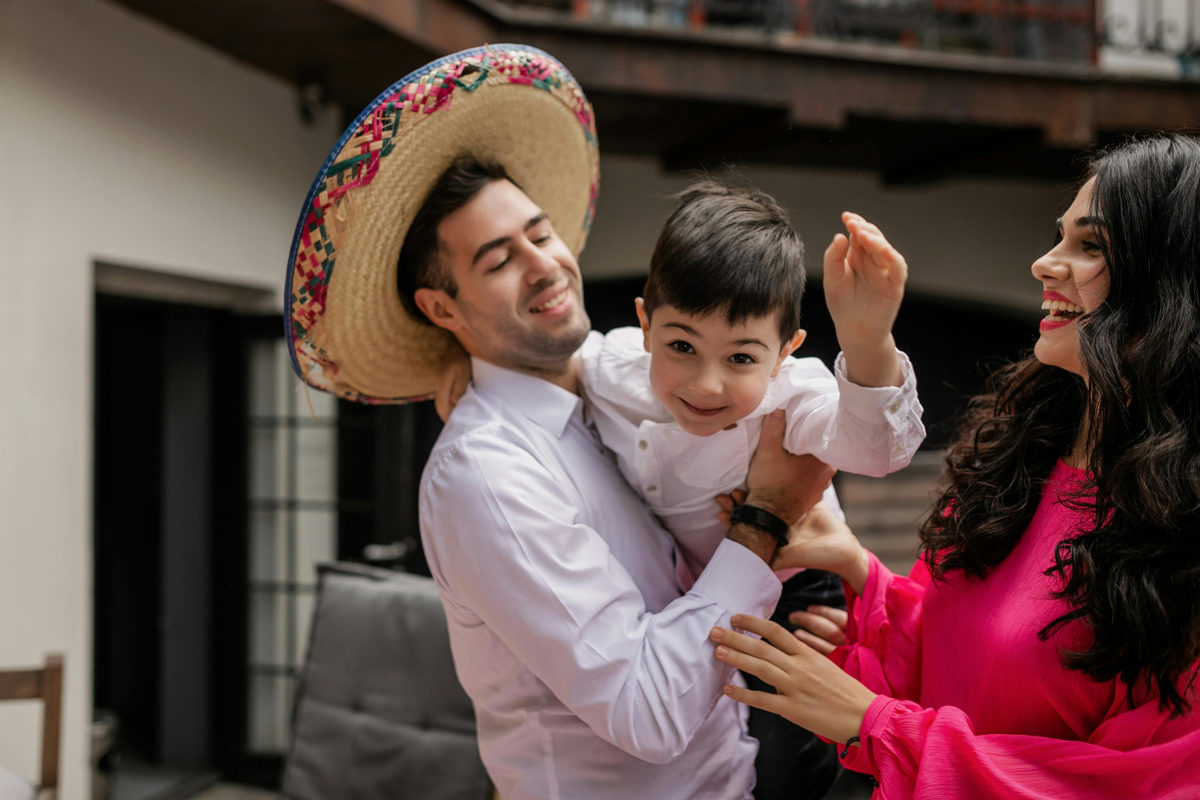 Dos adultos sosteniendo a un niño sonriente