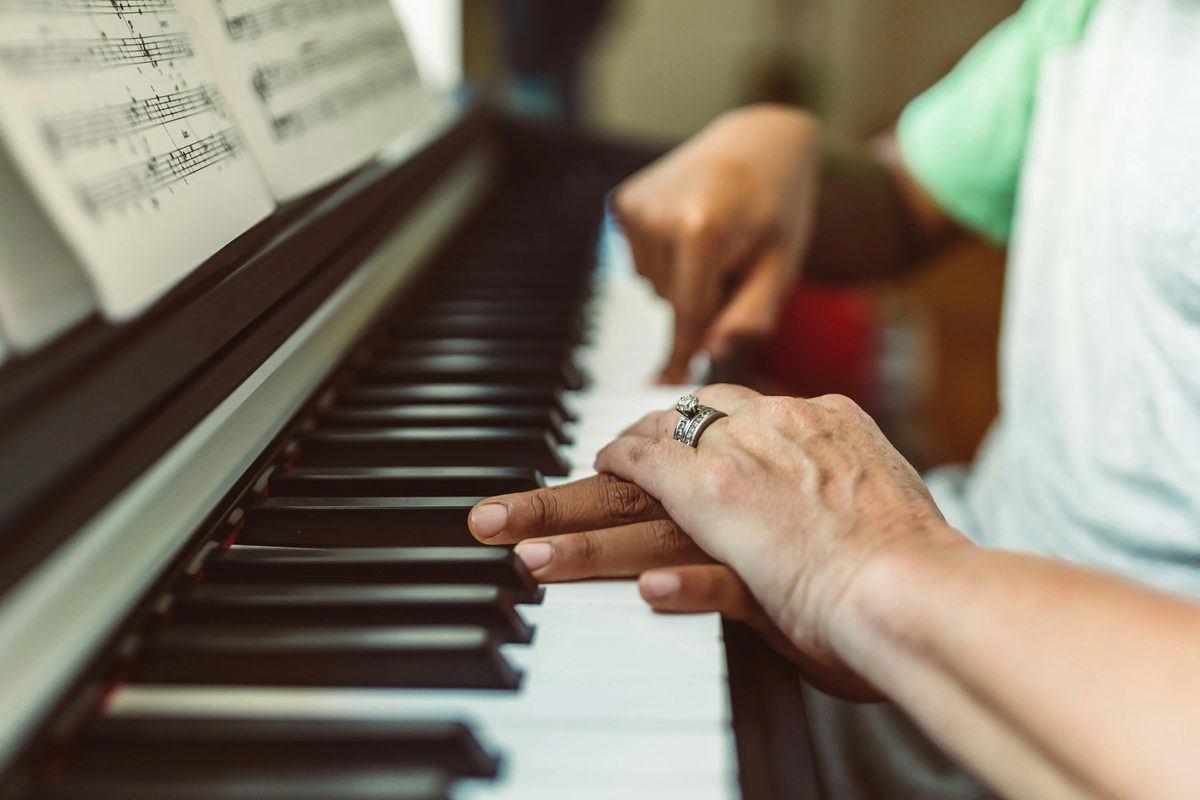 niño aprendiendo a tocar el piano con uno de sus padres