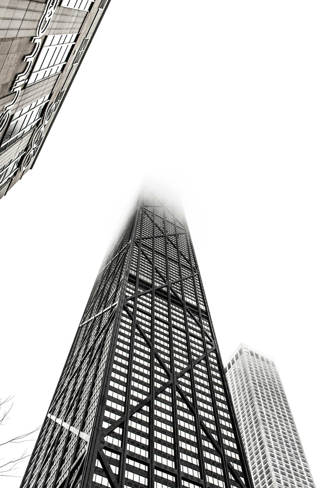 Black-and-white view of a skyscraper rising into fog