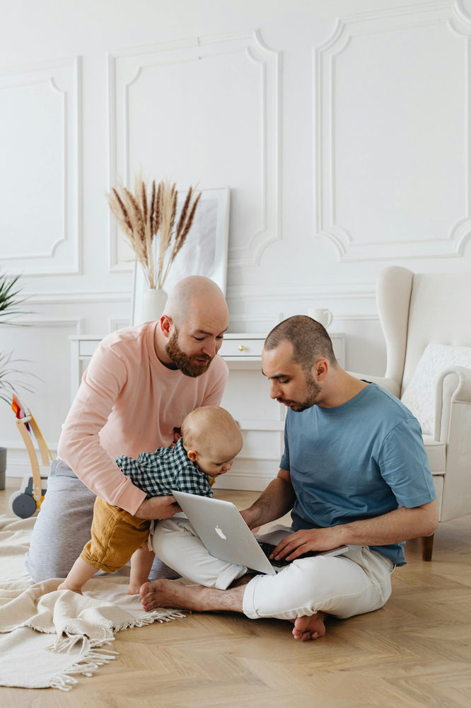 Dos adultos leyendo con un niño en un sofá.