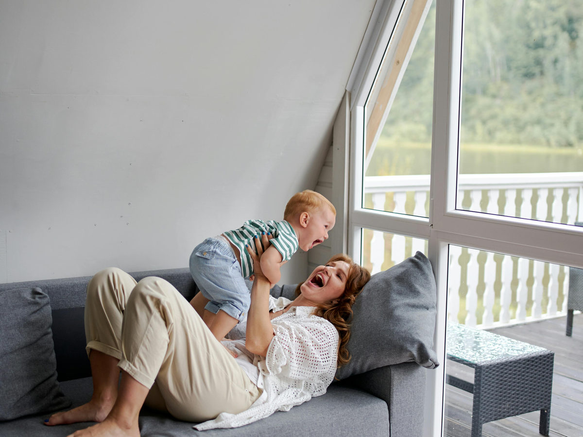 An adult and child playing on a sofa.