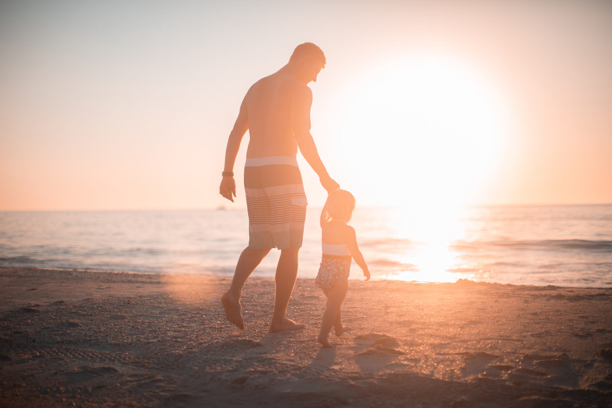 father and daughter walking on beach