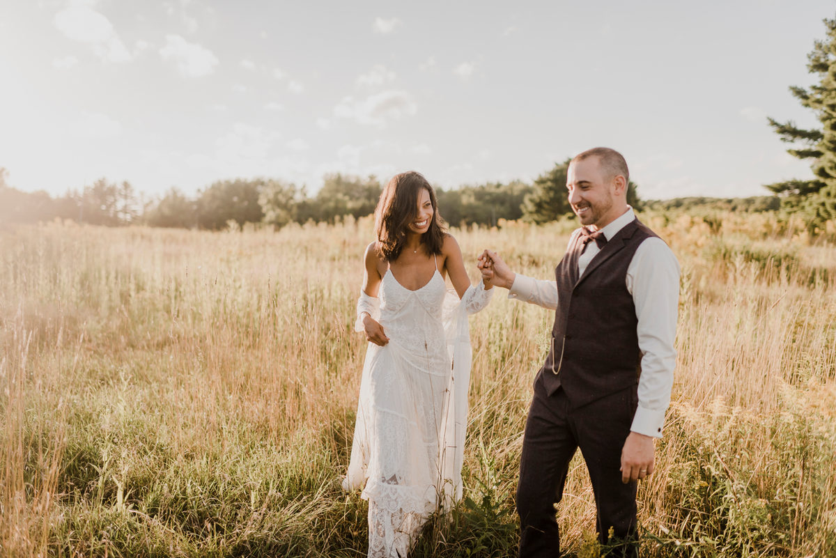 Dos personas vestidas de boda caminando por un campo soleado