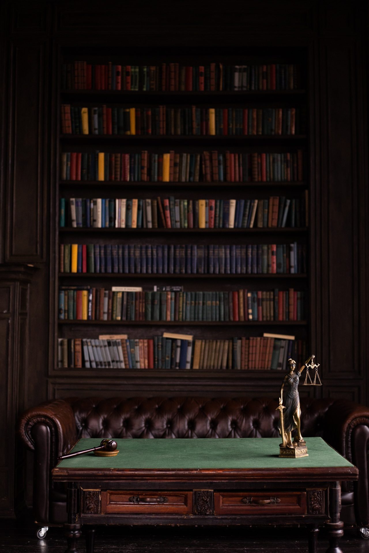 Bookshelves behind a desk with a gavel and a justice figurine.