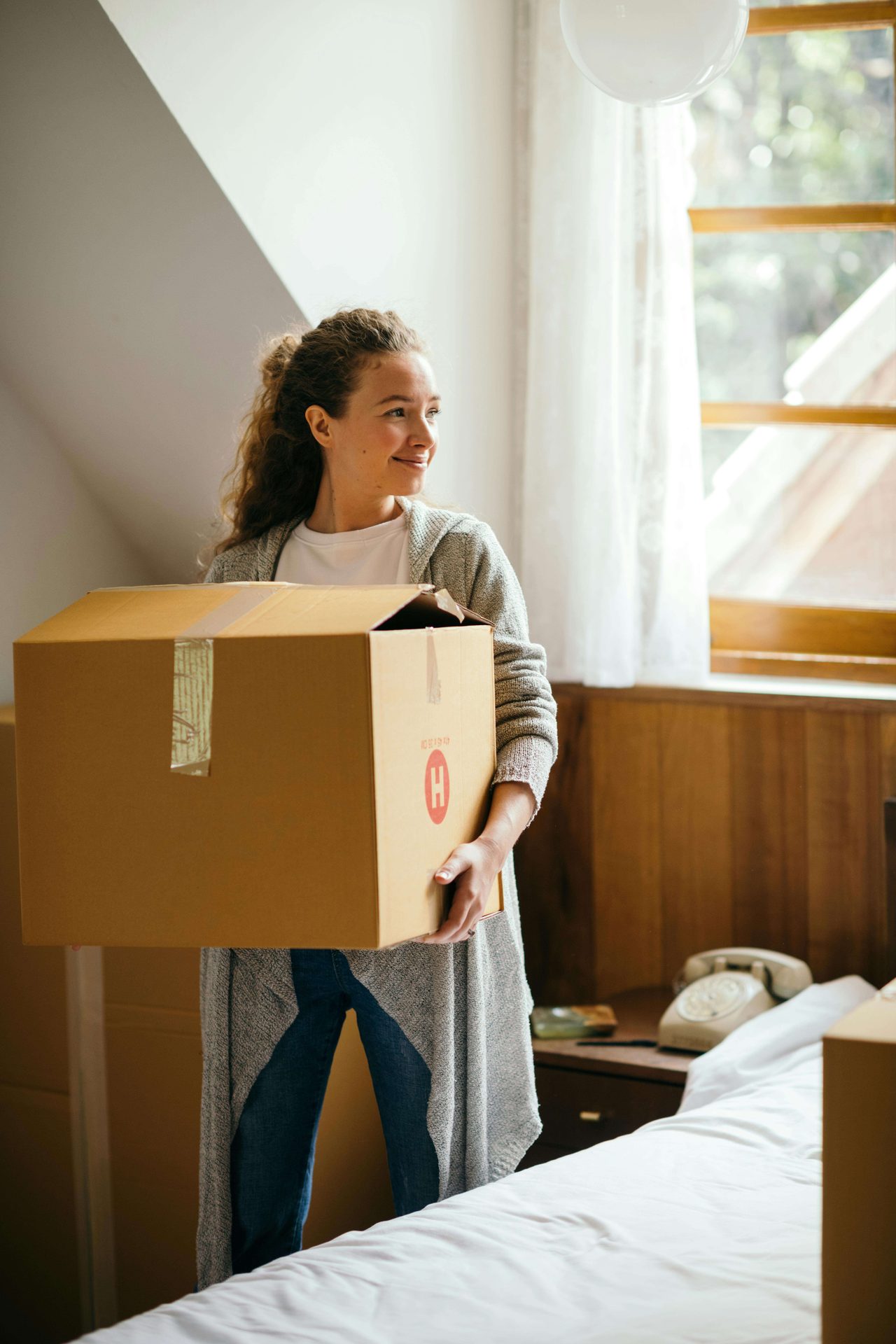 Woman carrying a moving box in a bedroom