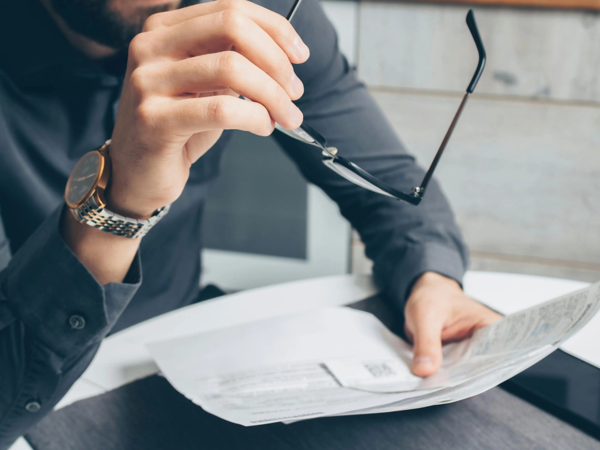 Person holding eyeglasses while reviewing papers.
