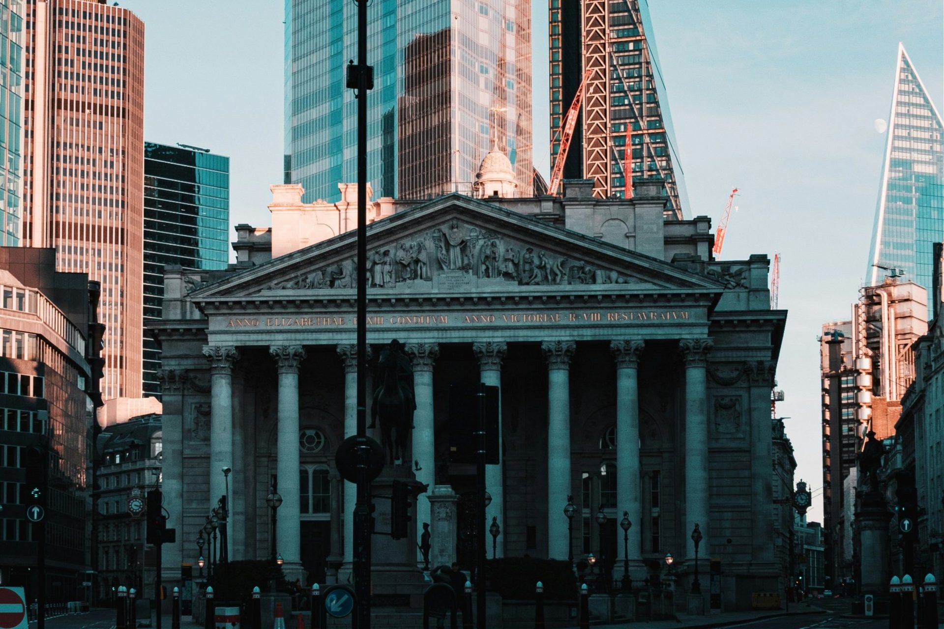 A stone building with a columned entrance surrounded by modern towers.