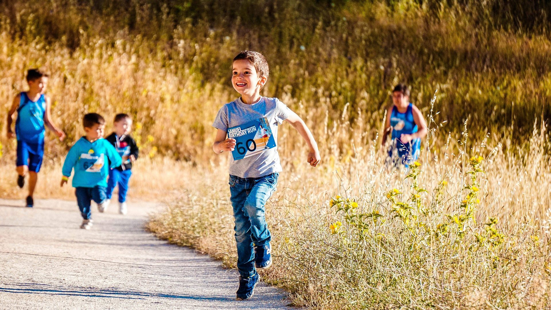 Niños corriendo por un sendero entre hierba alta