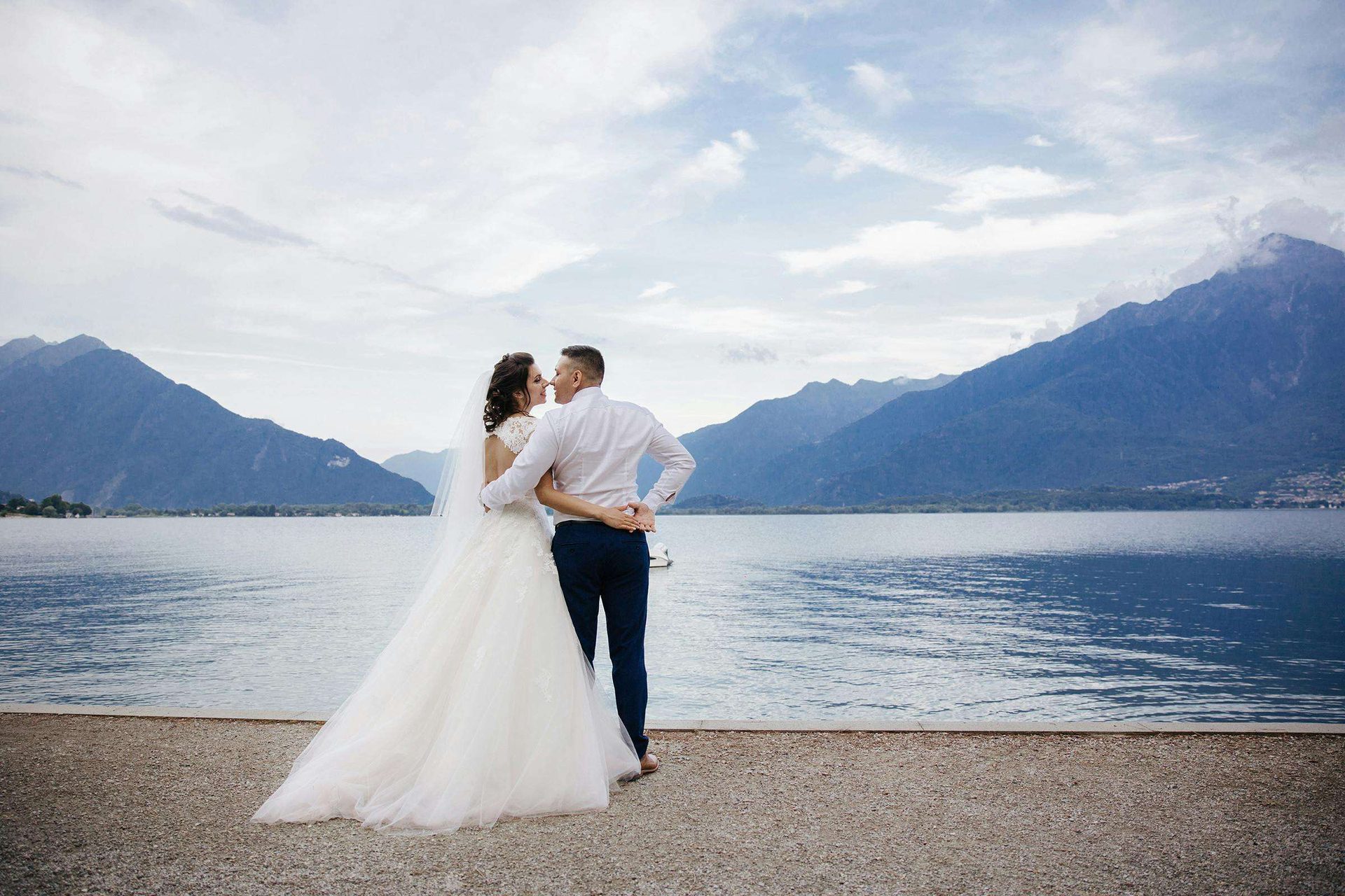 bride and groom kissing in front of lake