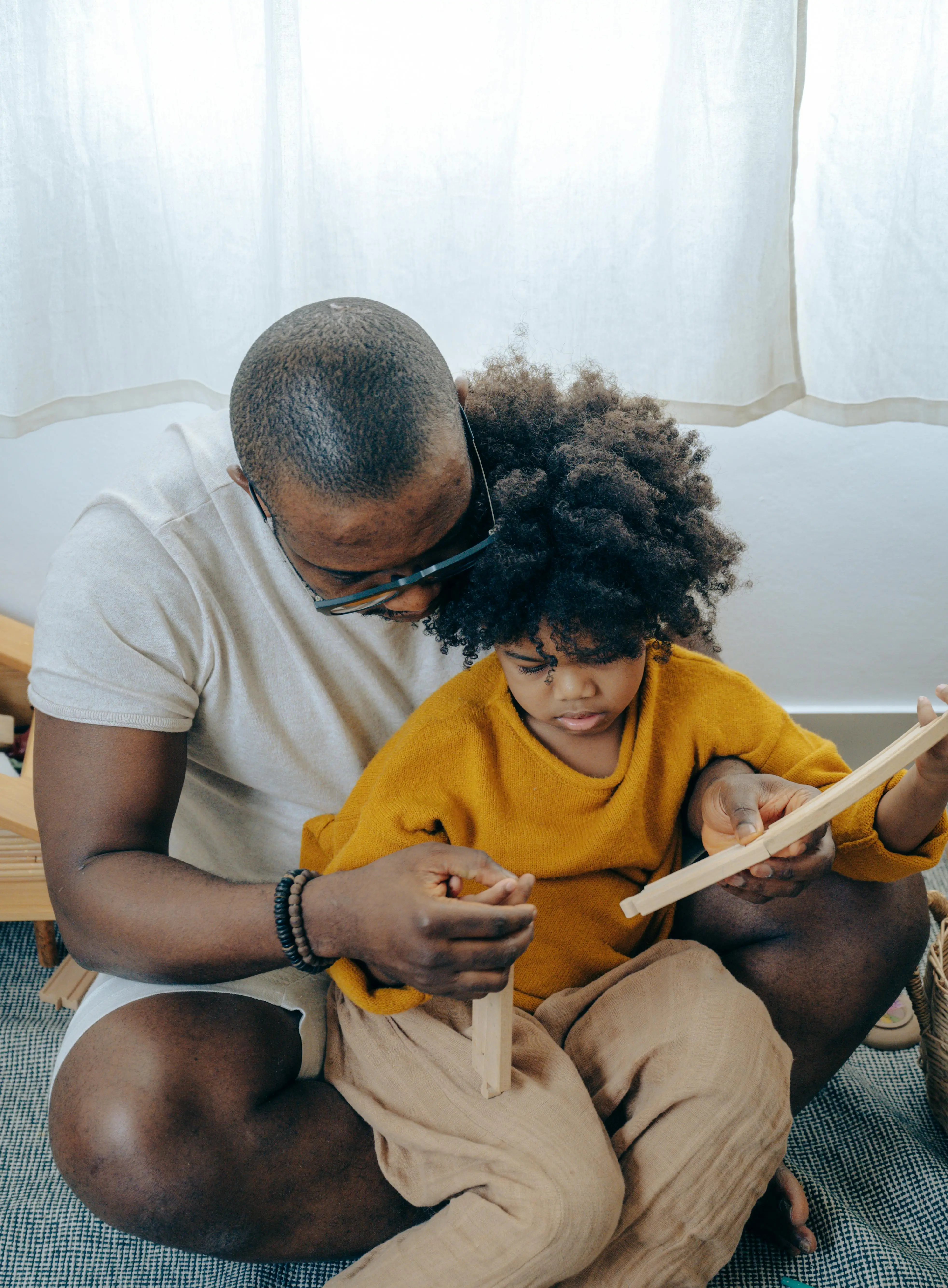 A man and a child playing with wooden pieces on the floor.