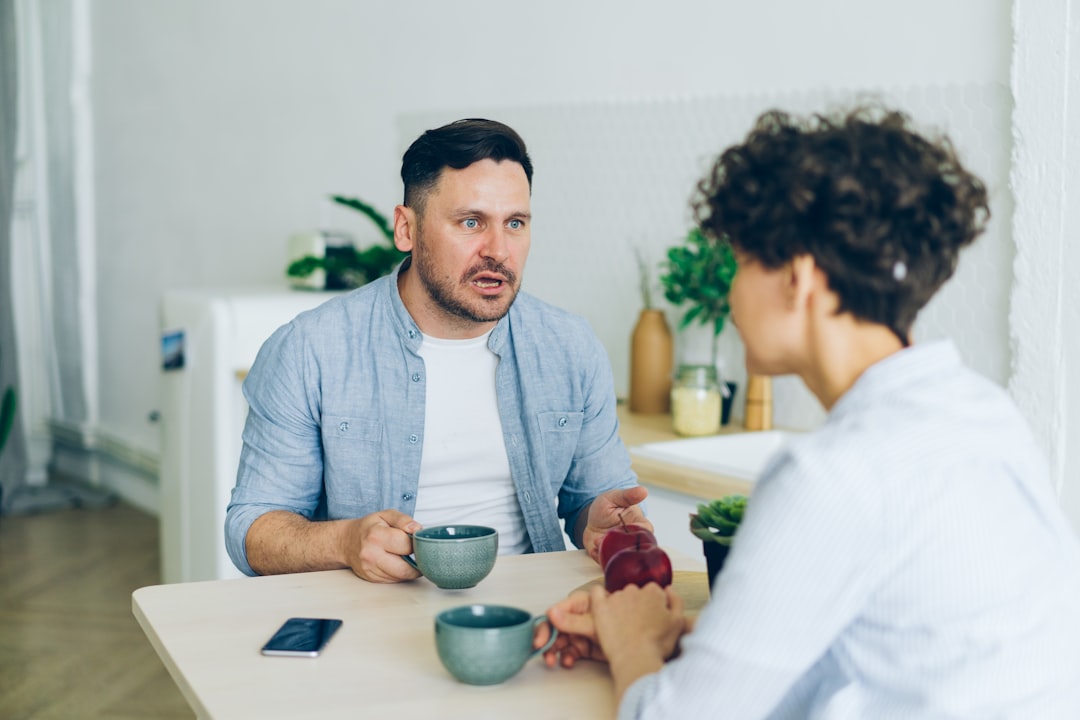 Dos adultos hablando en una mesa de cocina.