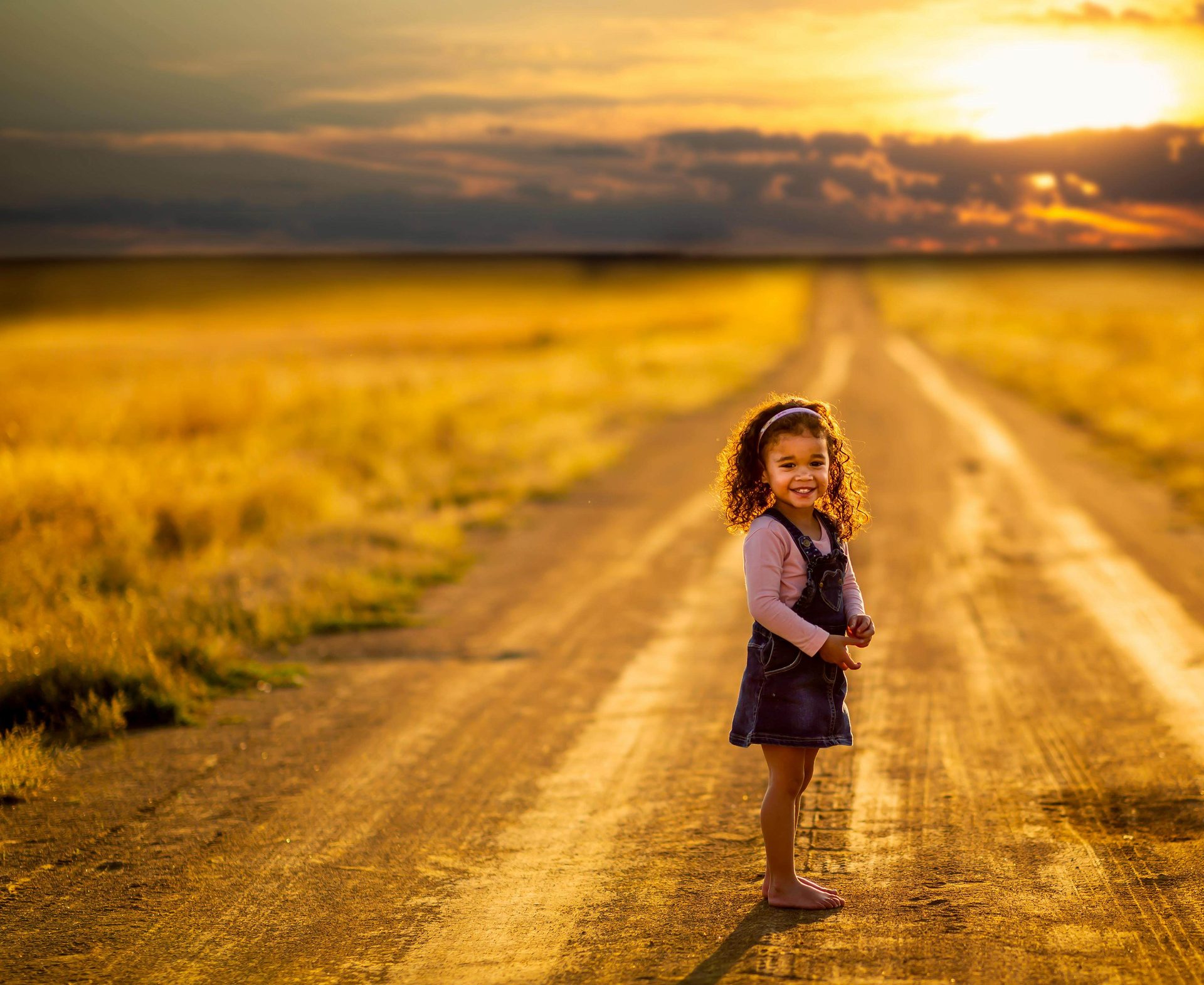 Niña pequeña sonriendo en un camino del campo