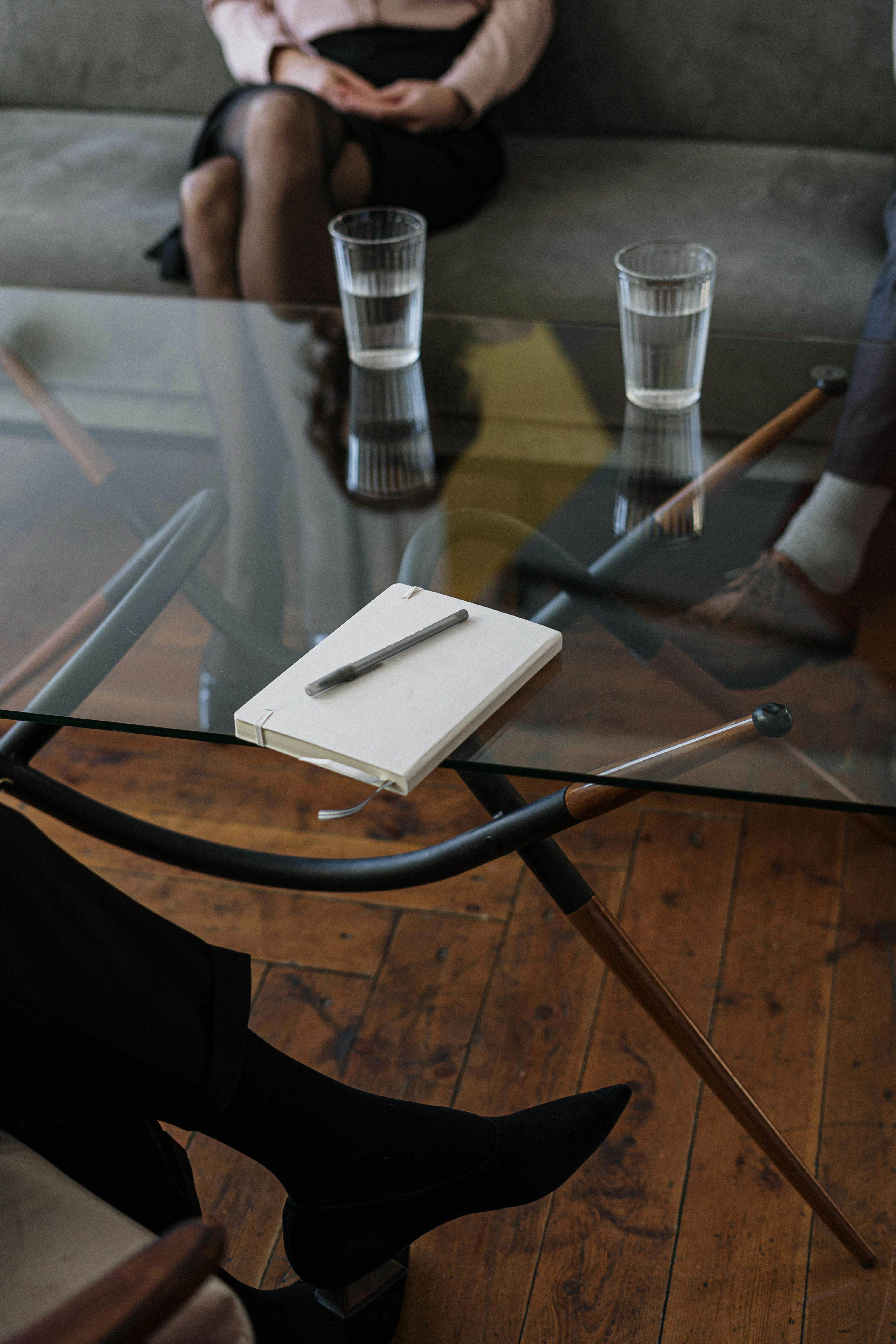 Una persona escribiendo en un cuaderno junto a dos vasos.