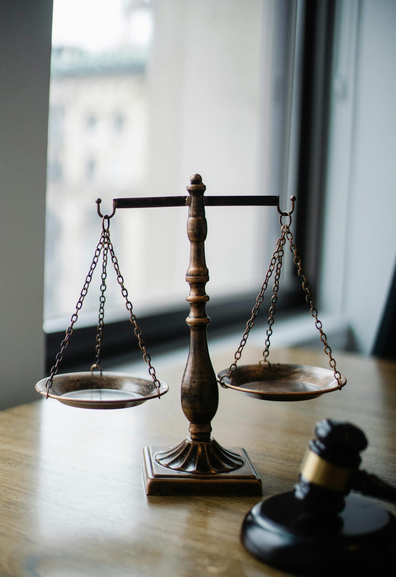 Balanza metálica de la justicia junto a un mazo de madera sobre un escritorio.