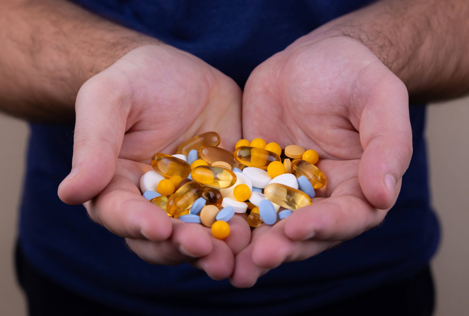 Hands holding assorted pills.