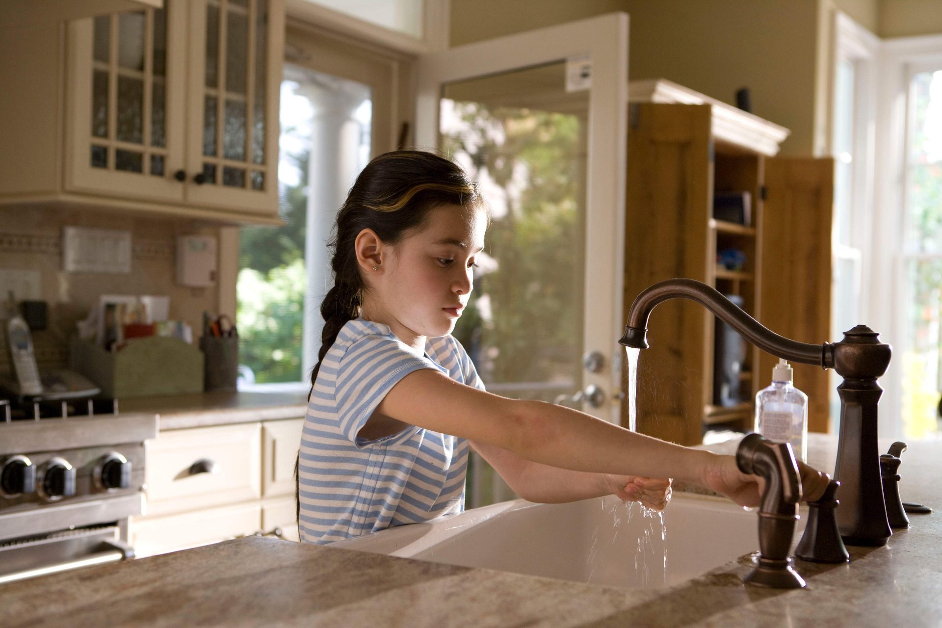 child washing hands in kitchen
