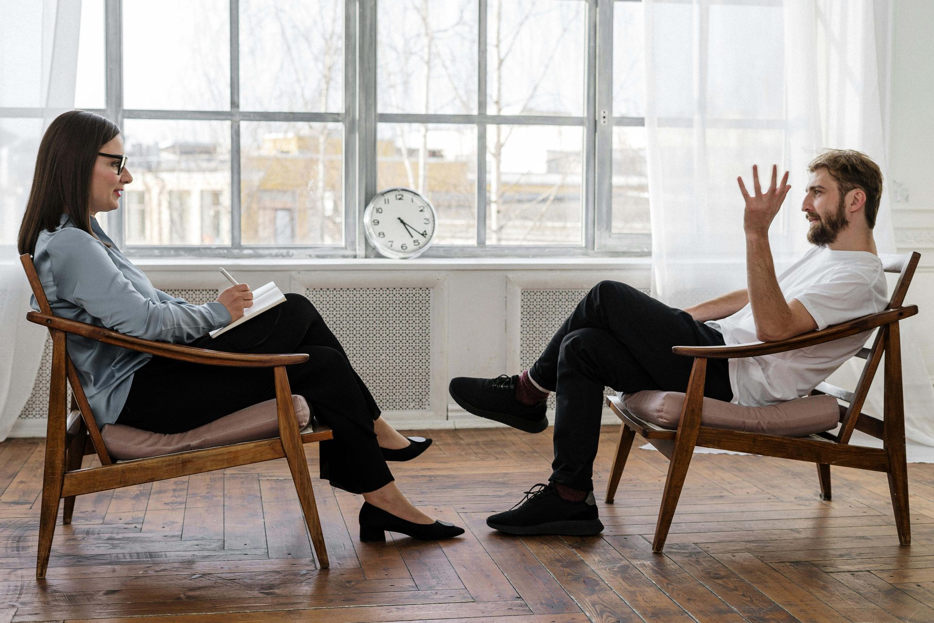 Two people talking in armchairs, with one taking notes.