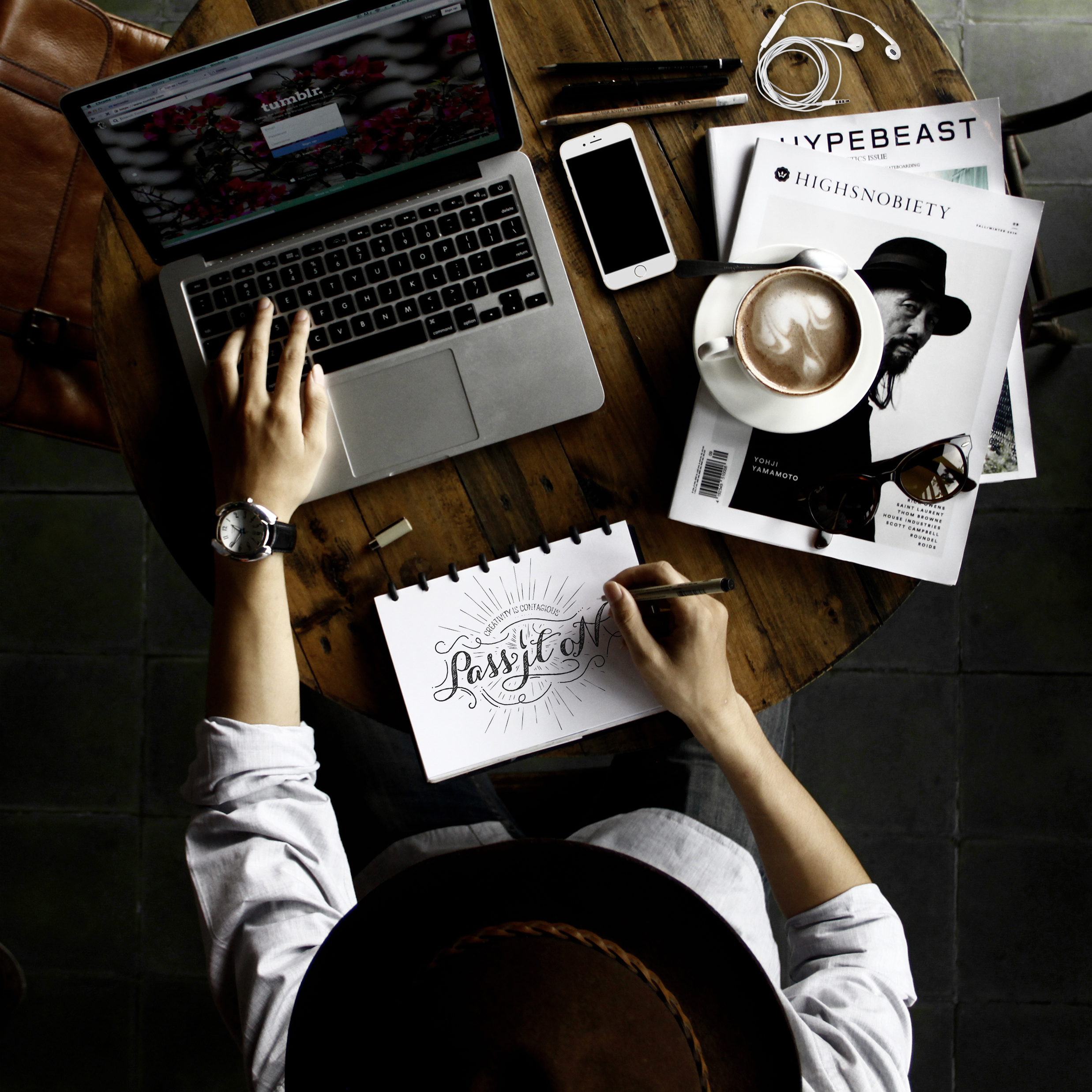 Person writing in a notebook beside a laptop and coffee.